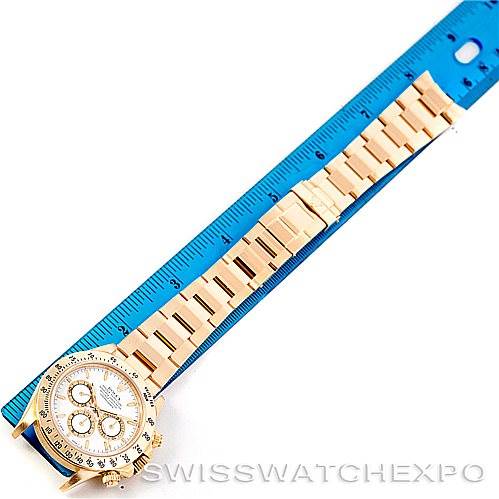 The Rolex Daytona 16528 Men's Yellow Gold White Dial 16528 Men's Yellow Gold White Dial watch is shown laid flat next to a blue ruler, displaying its full bracelet and dial from a top-down angle.