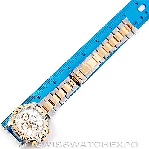 The photo shows the full length of a Rolex Daytona 16523 Men's Steel and Gold (two tone) White Dial 16523 Men's Steel and Gold (two tone) White Dial watch, including the face and band, with a blue ruler for scale.