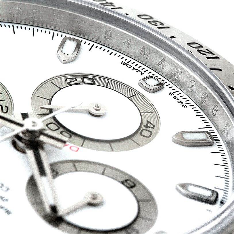 This close-up image of the Rolex Daytona 116520 Men's Stainless Steel White Dial 116520 Men's Stainless Steel White Dial watch shows its dial, chronograph sub-dials, and part of the bezel with engraved markers.