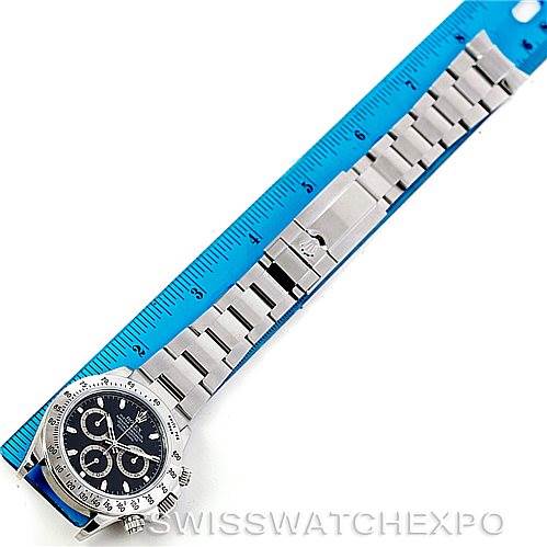 The image shows a Rolex Daytona 116520 Men's Stainless Steel Black Dial 116520 Men's Stainless Steel Black Dial watch laid flat with its bracelet fully extended alongside a blue ruler.