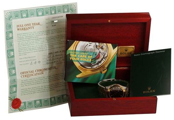 The image shows a Rolex Daytona 116523 Men's Stainless Steel Black Dial 116523 Men's Stainless Steel Black Dial watch in its box, along with warranty papers and care booklets, displayed from a front angle.