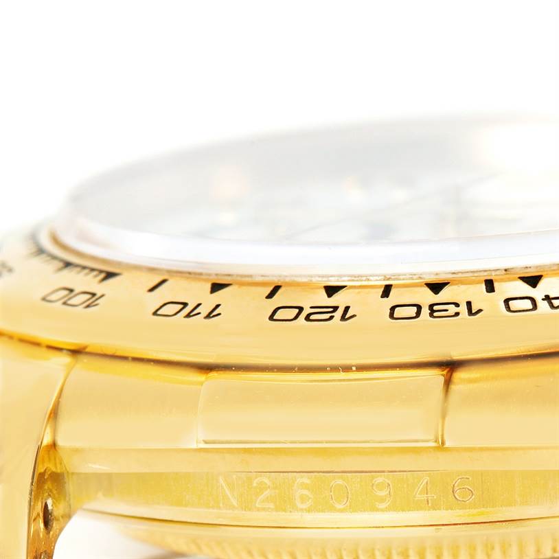 This close-up angle shows the bezel and part of the case of the Rolex Daytona 16518 Men's Yellow Gold White Dial 16518 Men's Yellow Gold White Dial watch, including some engraved details.