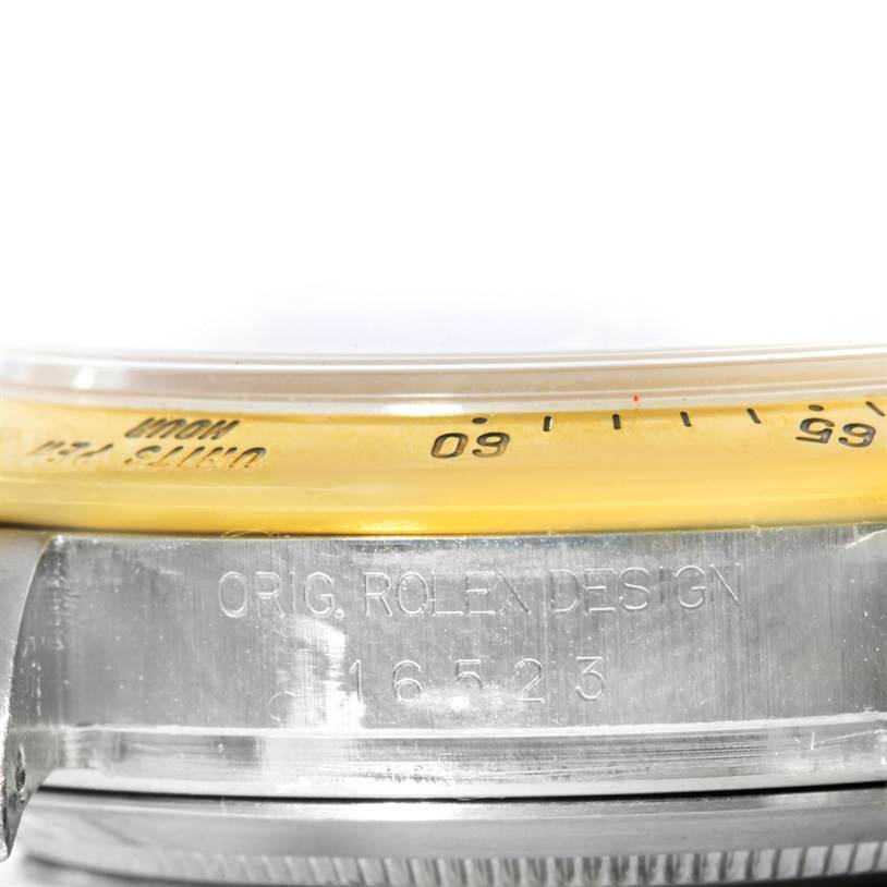 The image shows a close-up angle of the bezel and the case side of a Rolex Daytona 16523 Men's Steel and Gold (two tone) White Dial 16523 Men's Steel and Gold (two tone) White Dial watch, highlighting the model inscription.