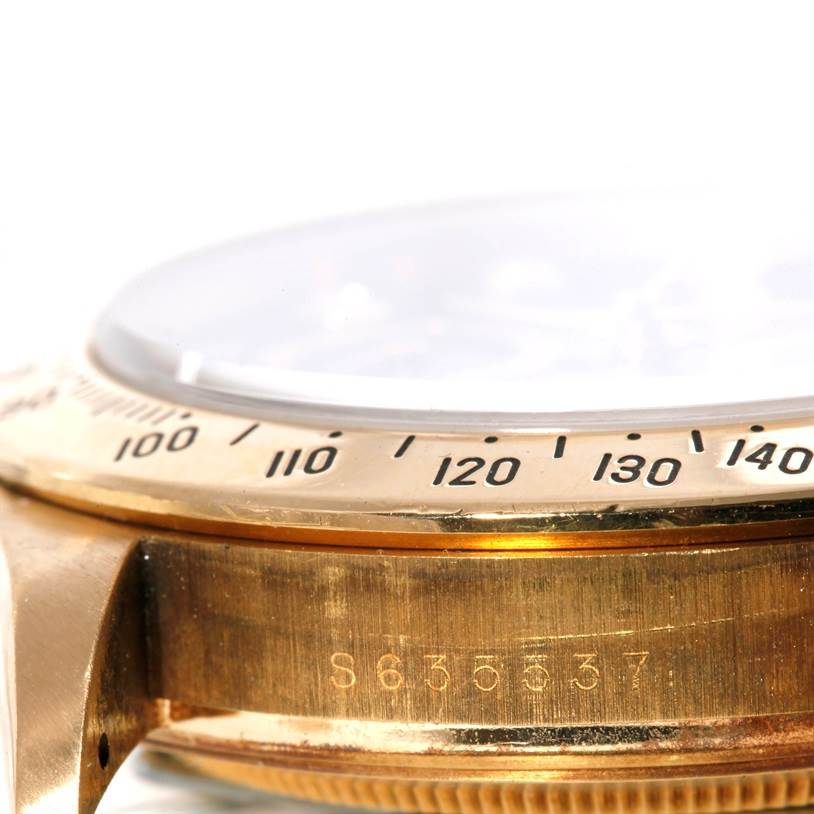 The image shows a close-up side view of a Rolex Daytona Men's Yellow Gold Black Dial Men's Yellow Gold Black Dial watch, highlighting the bezel with tachymeter and part of the case.