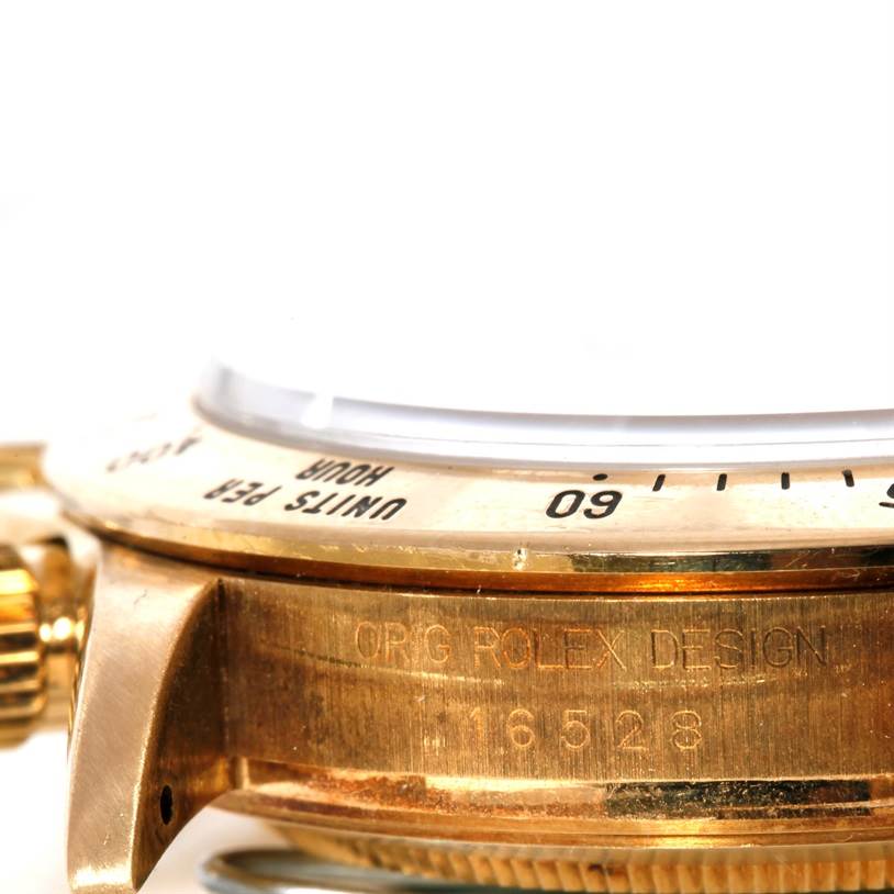 This close-up angle of the Rolex Daytona Men's Yellow Gold Black Dial Men's Yellow Gold Black Dial watch shows part of the bezel, crown, and case with the engraved model number "16528."