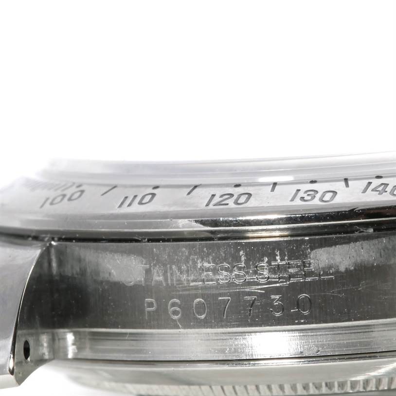 Side view of a Rolex Daytona 116520 Men's Stainless Steel White Dial 116520 Men's Stainless Steel White Dial watch showing the bezel with tachymeter scale and part of the case with engraved serial number.