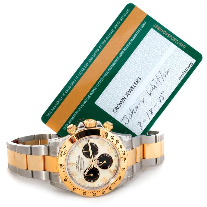 The image shows a Rolex Daytona 116523 Men's Steel and Gold (two tone) White Dial 116523 Men's Steel and Gold (two tone) White Dial watch with a gold and silver bracelet, placed in front of a green warranty card.