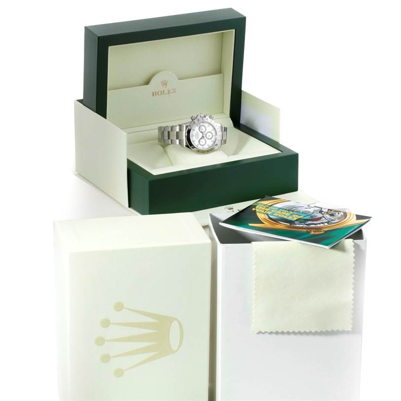 The Rolex Daytona 116520 Men's Stainless Steel White Dial 116520 Men's Stainless Steel White Dial watch is shown in a green and cream box along with its accessories, including a booklet and cleaning cloth.