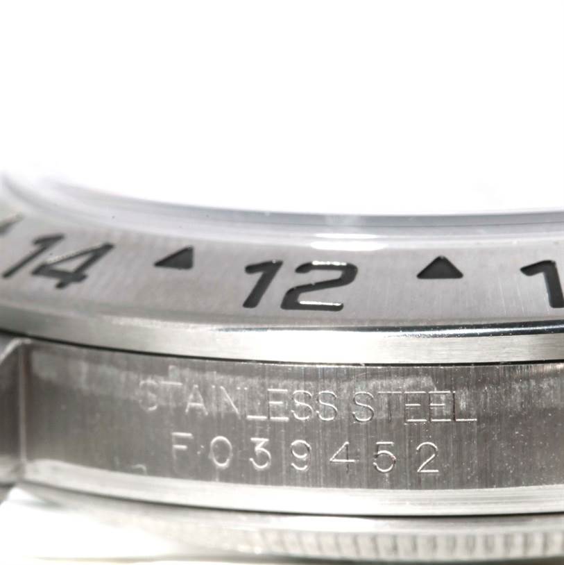 The image shows a close-up angle of the bezel and part of the case of a Rolex Explorer 16570 Men's Stainless Steel White Dial 16570 Men's Stainless Steel White Dial watch, highlighting the stainless steel inscription and serial number.