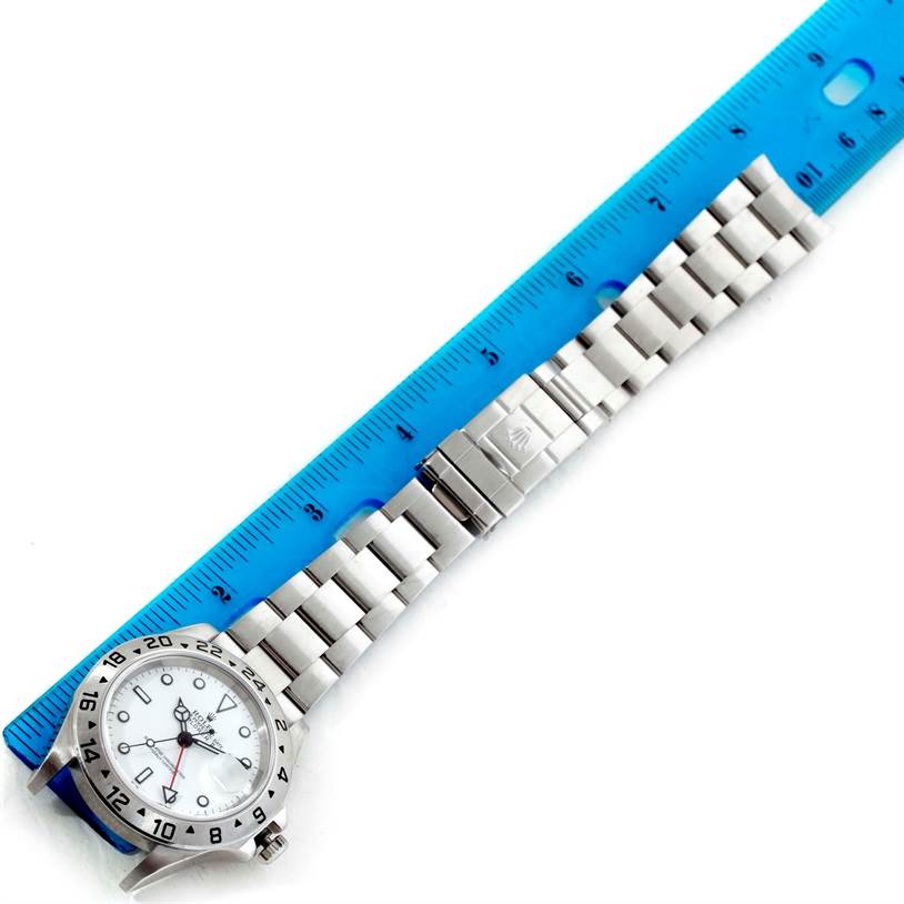 The Rolex Explorer 16570 Men's Stainless Steel White Dial 16570 Men's Stainless Steel White Dial model watch is shown in a top-down angle, with its face and bracelet next to a ruler for scale.