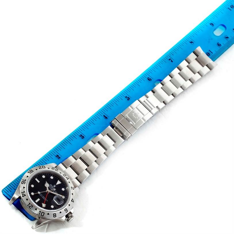 The Rolex Explorer 16570 Men's Stainless Steel Black Dial 16570 Men's Stainless Steel Black Dial watch is shown from the top angle, featuring the face, bezel, and bracelet alongside a blue ruler for scale.