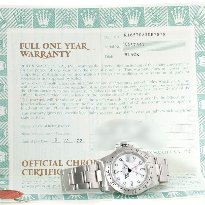 The image shows a Rolex Explorer 16570 Men's Stainless Steel White Dial 16570 Men's Stainless Steel White Dial watch laid flat on its back beside a full one-year warranty certificate.