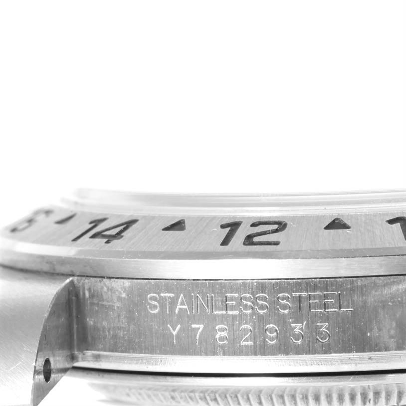 This close-up image of the Rolex Explorer 16570 Men's Stainless Steel White Dial 16570 Men's Stainless Steel White Dial watch shows the bezel and part of the case with serial number engraving.