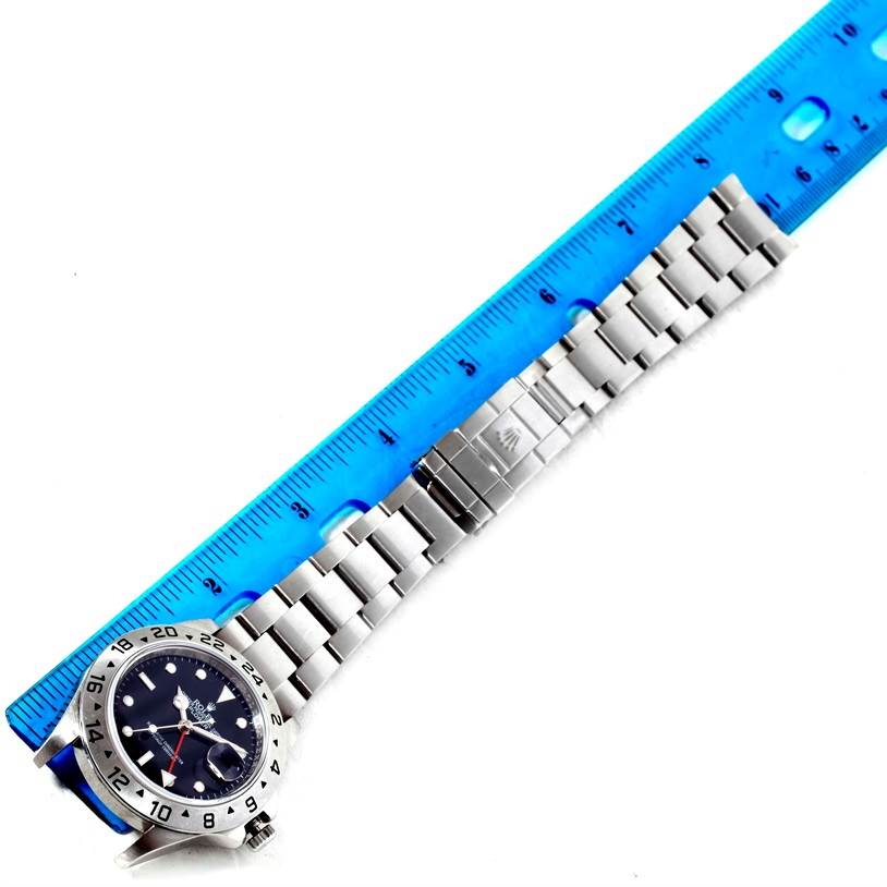 The image shows a Rolex Explorer 16570 Men's Stainless Steel Black Dial 16570 Men's Stainless Steel Black Dial watch laid flat with a blue ruler measuring its metal bracelet.