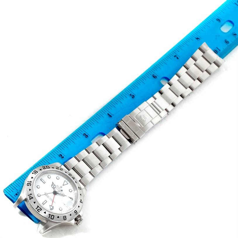 The Rolex Explorer 16570 Men's Stainless Steel White Dial 16570 Men's Stainless Steel White Dial watch is shown from a top-down angle, including the face, bezel, and the full bracelet placed next to a ruler.