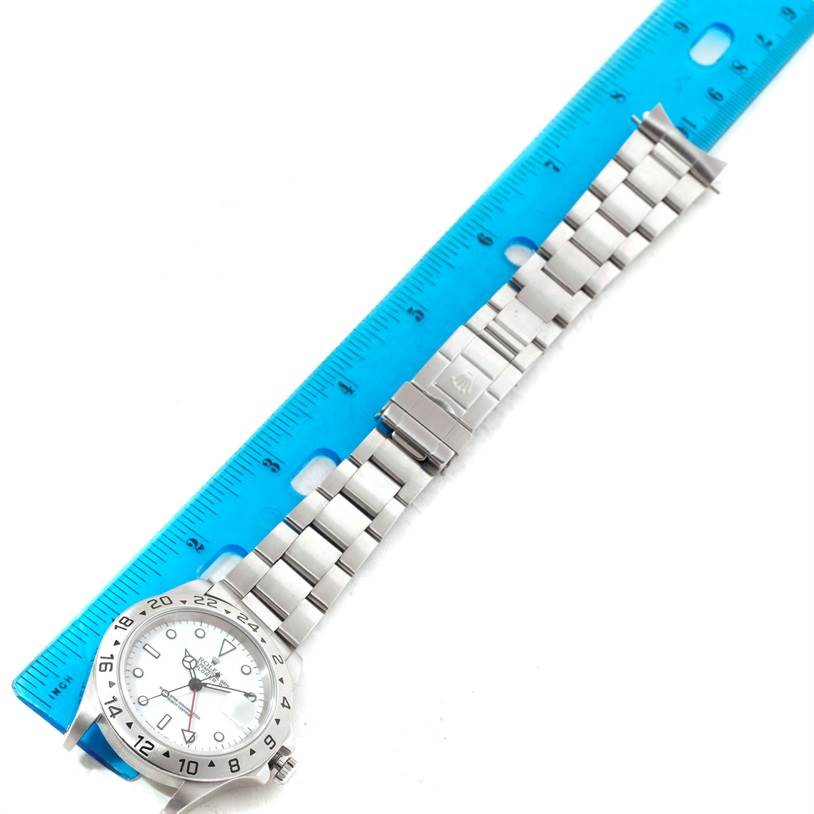 The image shows a Rolex Explorer 16570 Men
s Stainless Steel White Dial 16570 Men
s Stainless Steel White Dial watch laid flat next to a blue ruler, highlighting its bracelet length and clasp.