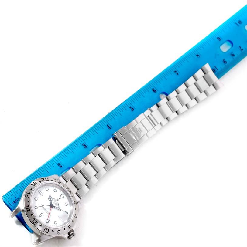 The image shows a stainless steel Rolex Explorer 16570 Men's Stainless Steel White Dial 16570 Men's Stainless Steel White Dial watch laid next to a blue ruler, highlighting the watch face and bracelet.