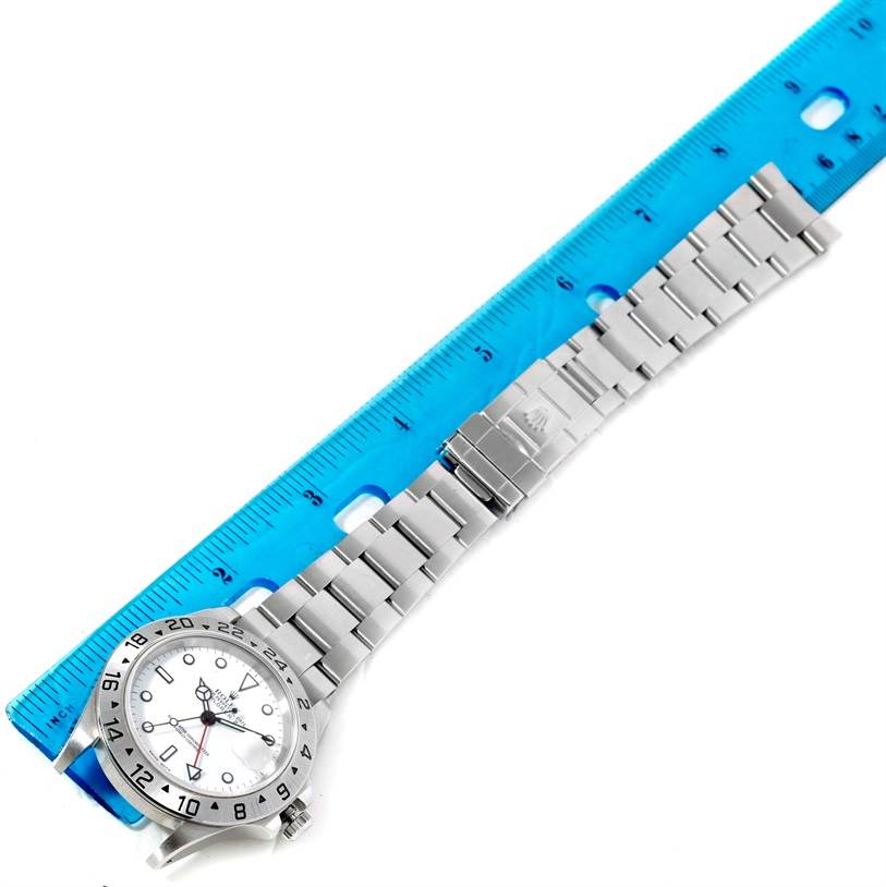 The image shows a Rolex Explorer 16570 Men's Stainless Steel White Dial 16570 Men's Stainless Steel White Dial watch laid next to a blue ruler, displaying its face, bracelet, and clasp.