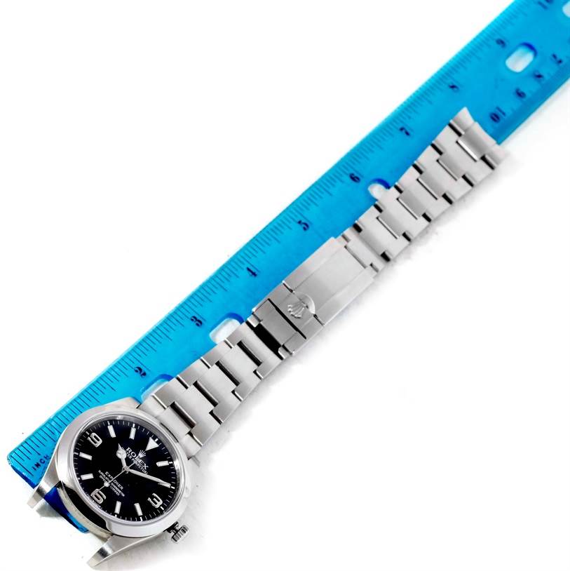 The image shows a Rolex Explorer 214270 Men's Stainless Steel Black Dial 214270 Men's Stainless Steel Black Dial watch laid flat next to a ruler, displaying the watch face, bracelet, and clasp.