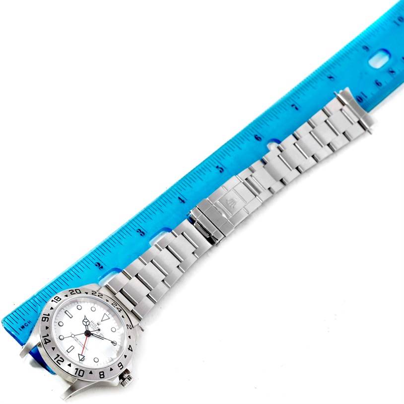 The image shows a Rolex Explorer 16570 Men's White Dial 16570 Men's White Dial watch laid flat beside a blue ruler, displaying its band and face.