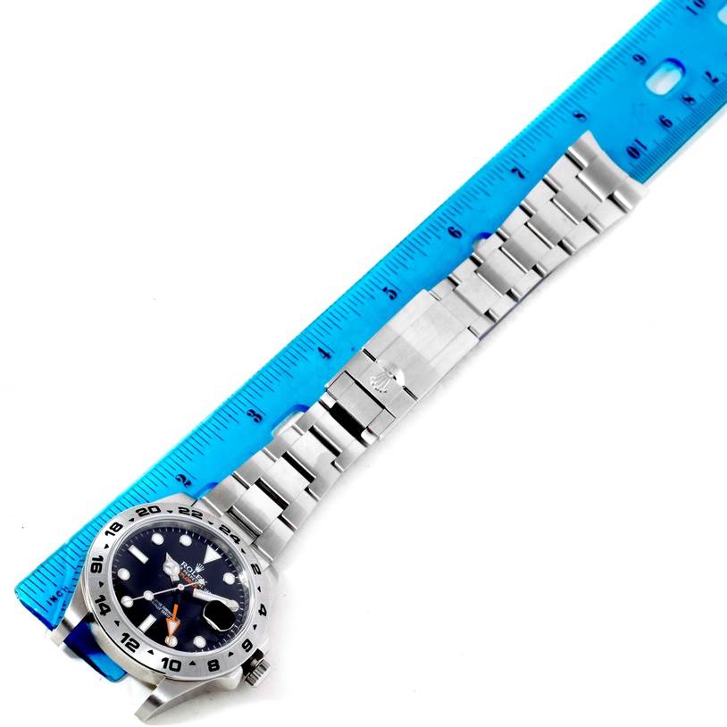 The image shows a Rolex Explorer 216570 Men's Stainless Steel Black Dial 216570 Men's Stainless Steel Black Dial watch laid flat next to a blue ruler, displaying the face, bezel, and full bracelet.