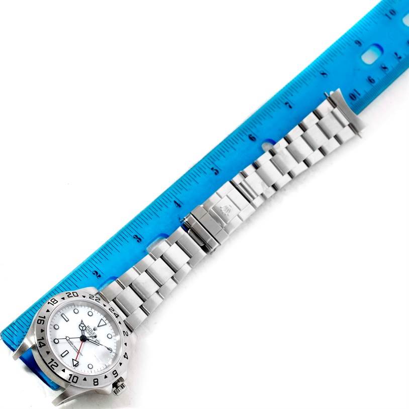 The Rolex Explorer 16570 Men's Stainless Steel White Dial 16570 Men's Stainless Steel White Dial watch is shown from a top view, alongside a blue ruler measuring its bracelet length.