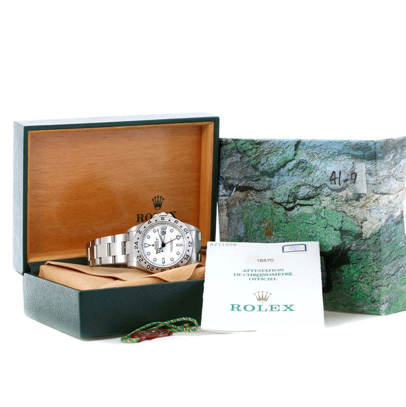 The image shows a Rolex Explorer 16570 Men's Stainless Steel White Dial 16570 Men's Stainless Steel White Dial watch at a slight angle, placed inside its open box, alongside warranty papers and packaging.