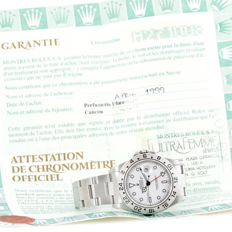 The image shows a Rolex Explorer 16570 Men's Stainless Steel White Dial 16570 Men's Stainless Steel White Dial watch lying flat on its side, alongside warranty and chronometer certification documents.