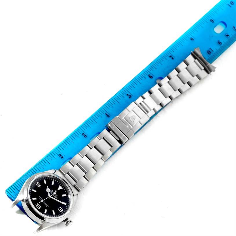 The image shows a Rolex Explorer 14270 Men's Stainless Steel Black Dial 14270 Men's Stainless Steel Black Dial watch laid flat with a blue ruler adjacent, displaying the full bracelet and the face of the watch.