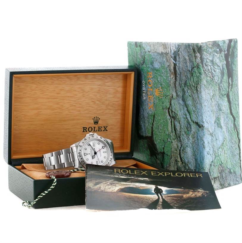 The image shows a Rolex Explorer 16570 Men
s Stainless Steel White Dial 16570 Men
s Stainless Steel White Dial watch at an angle inside an open box, with its accessories including the manual and outer packaging.