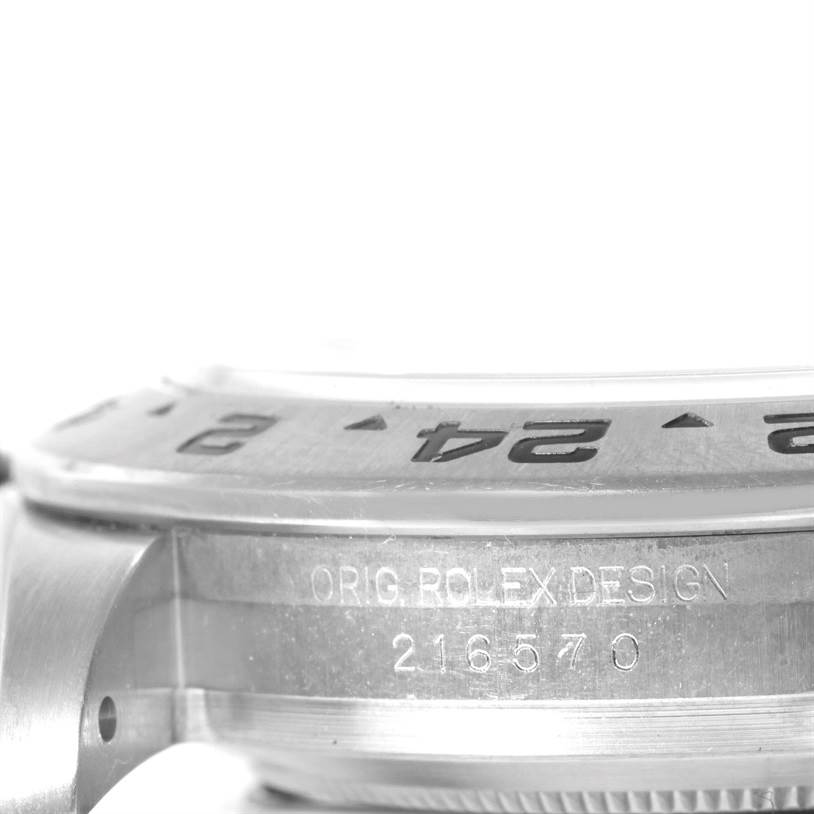 The image shows a close-up side view of the bezel and case of a Rolex Explorer 216570 Men's Stainless Steel White Dial 216570 Men's Stainless Steel White Dial model with engraved details.