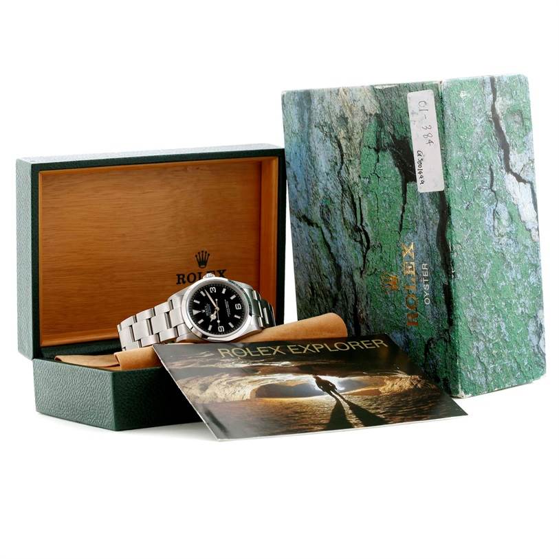 The Rolex Explorer 114270 Men's Stainless Steel Black Dial 114270 Men's Stainless Steel Black Dial watch is displayed at an angle, accompanied by its original box, packaging, and handbook.