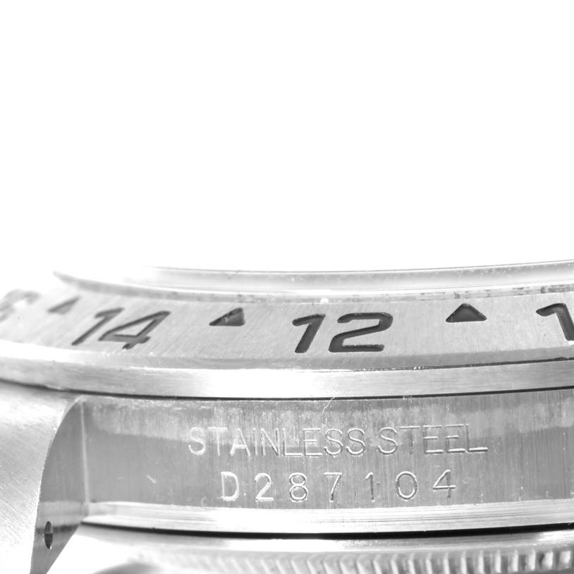 This close-up image of a Rolex Explorer 16570 Men's Stainless Steel White Dial 16570 Men's Stainless Steel White Dial watch shows the bezel with hour markers and part of the stainless steel case with the serial number engraved.