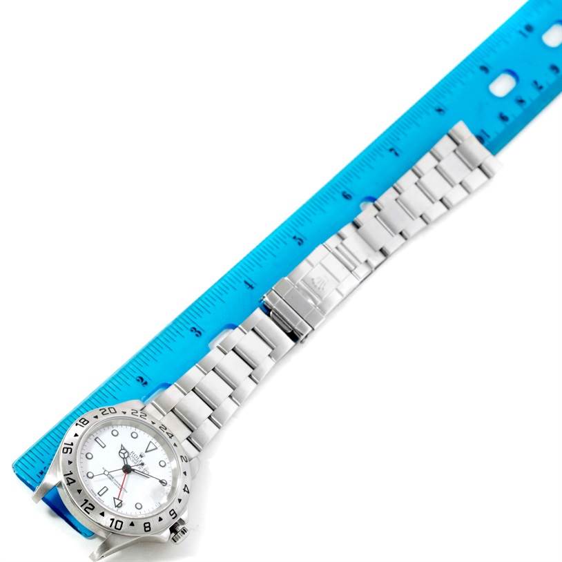 The image shows a Rolex Explorer 16570 Men's Stainless Steel White Dial 16570 Men's Stainless Steel White Dial watch laid flat against a ruler, displaying the face, bezel, and metal bracelet.