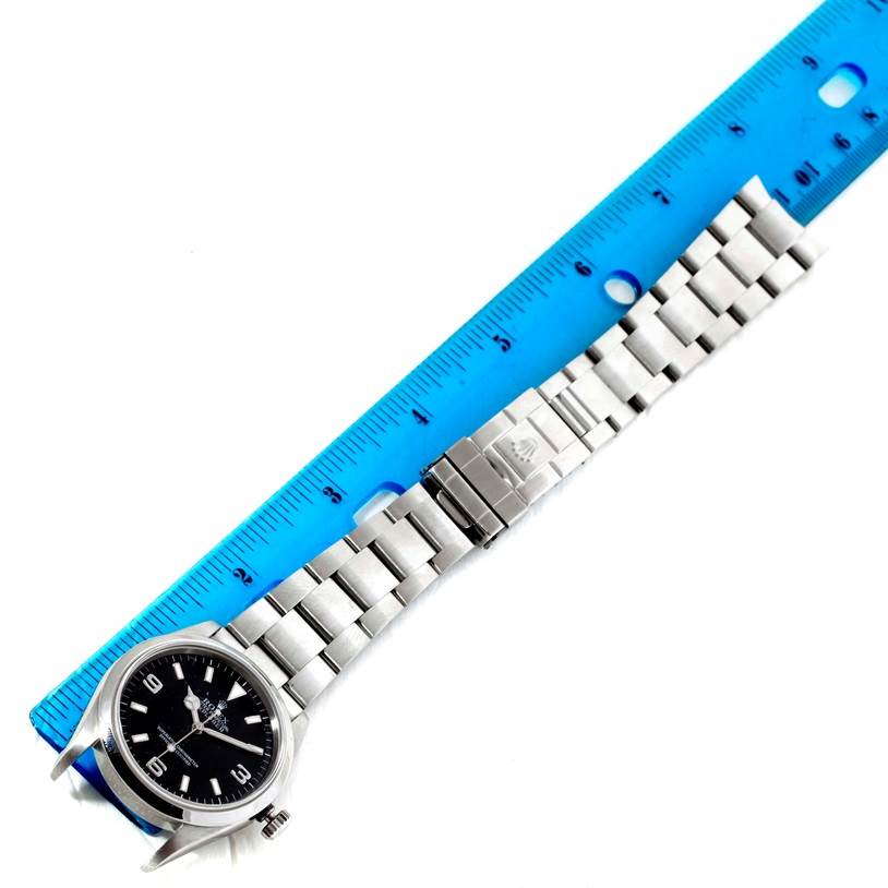 This image shows a Rolex Explorer 114270 Men's Stainless Steel Black Dial 114270 Men's Stainless Steel Black Dial watch laid flat with its face up and a blue ruler for scale, highlighting the dial and bracelet.