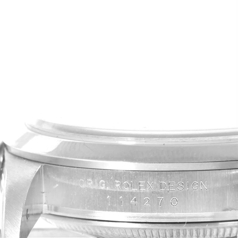 The image shows a close-up of the case side of a Rolex Explorer 114270 Men's Stainless Steel Black Dial 114270 Men's Stainless Steel Black Dial watch, highlighting the "ORIG. ROLEX DESIGN 114270" engraving.