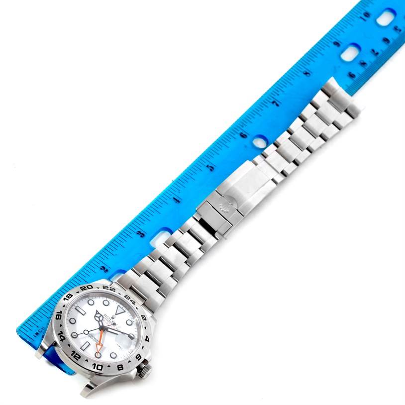 The image shows a Rolex Explorer 216570 Men's Stainless Steel White Dial 216570 Men's Stainless Steel White Dial model watch laid flat with its face, bezel, and bracelet visible, next to a blue ruler.