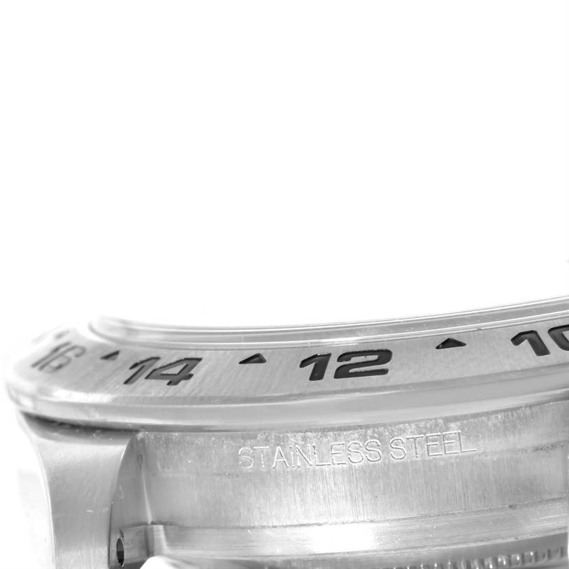 This close-up image of a Rolex Explorer 216570 Men's Stainless Steel White Dial 216570 Men's Stainless Steel White Dial watch shows a partial view of the bezel with engraved numerals and the stainless steel case.