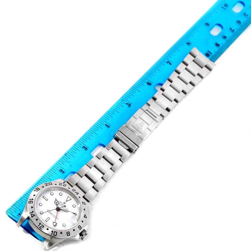 The image shows a Rolex Explorer 16570 Men's Stainless Steel White Dial 16570 Men's Stainless Steel White Dial watch laid flat, with a blue ruler next to its stainless steel bracelet and dial.