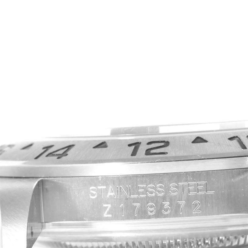 Close-up angled shot of a Rolex Explorer 16570 Men's Stainless Steel White Dial 16570 Men's Stainless Steel White Dial model showing the bezel, part of the dial, and the stainless steel engraving with serial number.