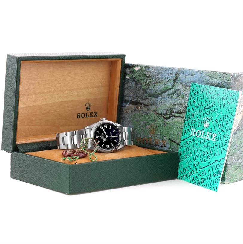 The Rolex Explorer 14270 Men's Stainless Steel Black Dial 14270 Men's Stainless Steel Black Dial watch is shown inside an open green and wood box with booklets placed beside it.