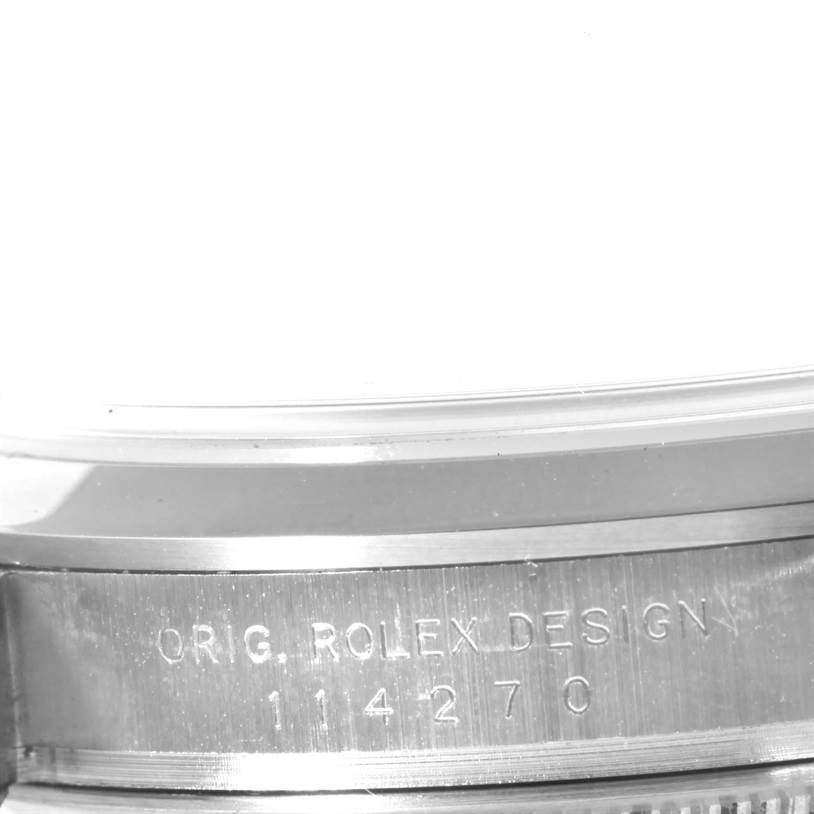 The image shows a close-up of the side of a Rolex Explorer 114270 Men's Stainless Steel Black Dial 114270 Men's Stainless Steel Black Dial watch case, displaying the inscription "ORIG. ROLEX DESIGN 114270."