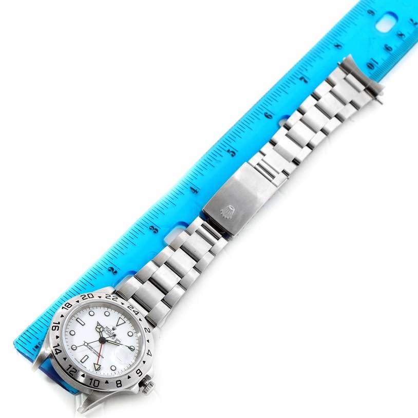 The Rolex Explorer 16570 Men's Stainless Steel Silver Dial 16570 Men's Stainless Steel Silver Dial watch is displayed with a full view of the bracelet, dial, and clasp alongside a blue ruler for scale.