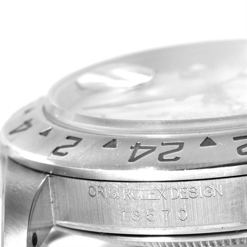 This image shows a close-up of the bezel, case, and part of the crystal of a Rolex Explorer 16570 Men's Stainless Steel White Dial 16570 Men's Stainless Steel White Dial watch, including its engraved reference number 16570.