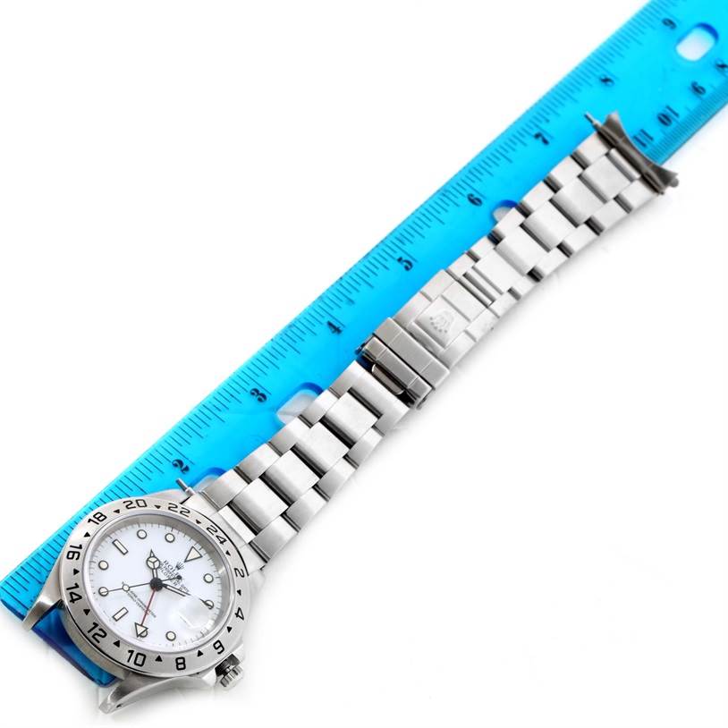 This image shows a horizontal view of a Rolex Explorer 16570 Men's Stainless Steel White Dial 16570 Men's Stainless Steel White Dial watch, including the face and bracelet, next to a blue ruler.