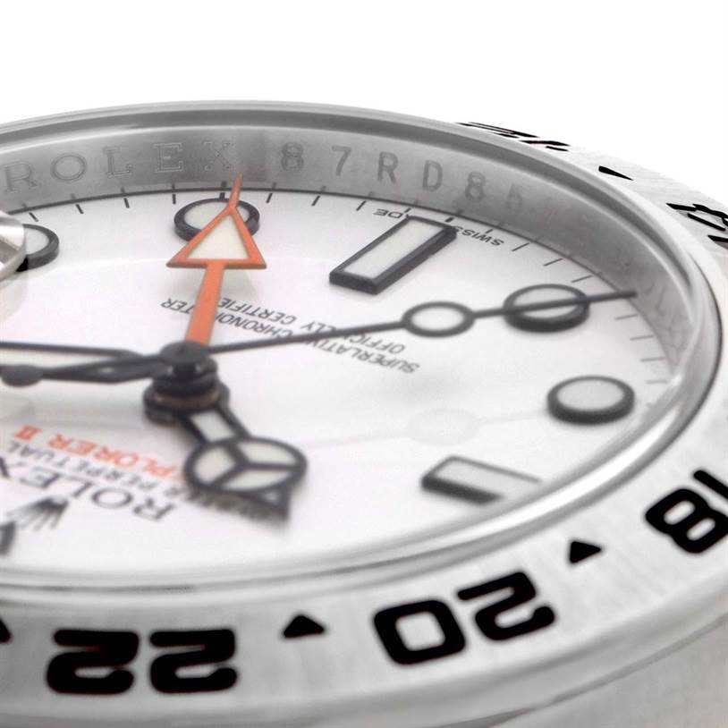 This close-up angle of a Rolex Explorer 216570WSO Men's Stainless Steel White Dial 216570WSO Men's Stainless Steel White Dial watch shows its white dial, orange 24-hour hand, black hour markers, and partial bezel.