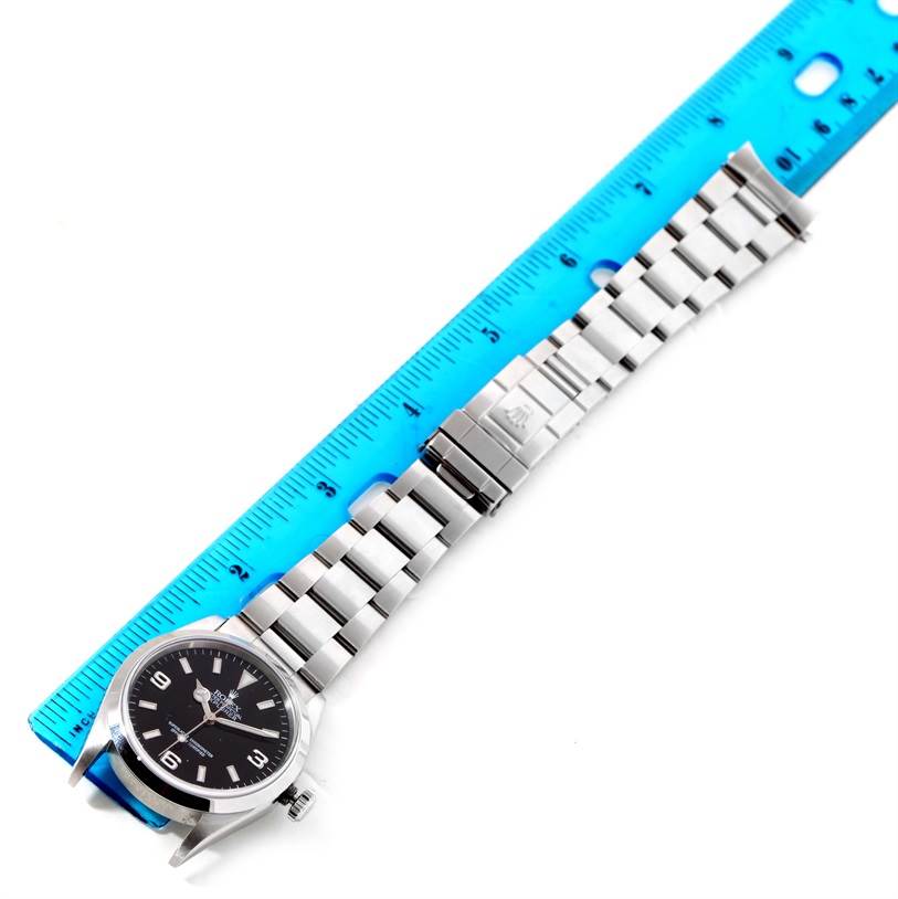 The image shows a Rolex Explorer 114270 Men's Stainless Steel Black Dial 114270 Men's Stainless Steel Black Dial watch laid flat next to a blue ruler, showcasing the dial, case, and metal bracelet.