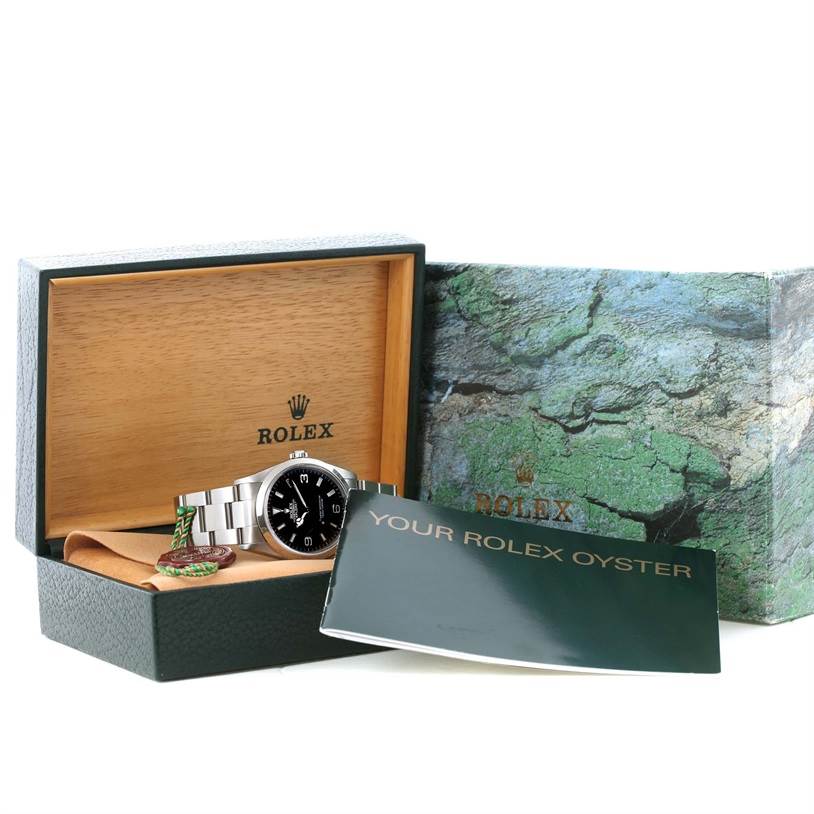 The Rolex Explorer 114270 Men's Stainless Steel Black Dial 114270 Men's Stainless Steel Black Dial watch is shown in its open box with a booklet and tag visible.