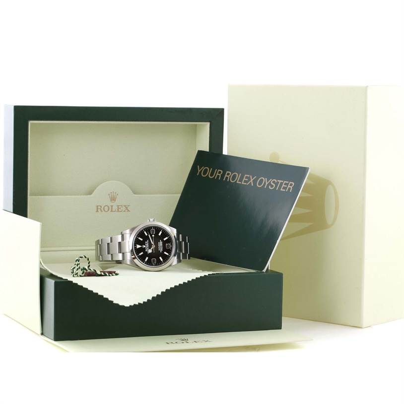 The Rolex Explorer 214270 Men's Stainless Steel Black Dial 214270 Men's Stainless Steel Black Dial watch is shown in its box with accompanying booklets and accessories, viewed from a front angle.