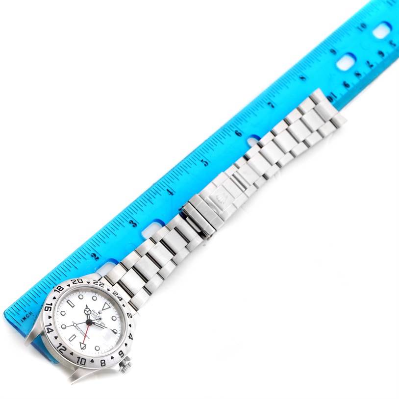 The image shows the full stainless steel bracelet and face of a Rolex Explorer 16570 Men's Stainless Steel White Dial 16570 Men's Stainless Steel White Dial model watch at a slight diagonal angle, with a blue ruler beside it.